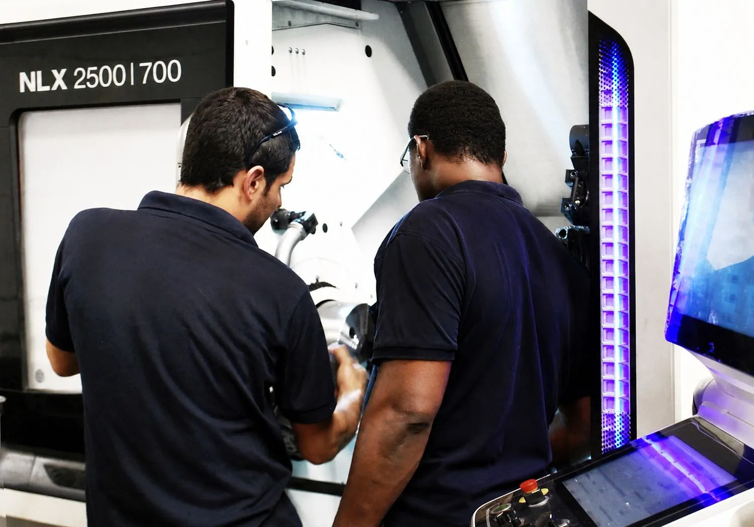 Dos técnicos de MSISAB trabajando en un torno CNC DMG MORI NLX 2500/700